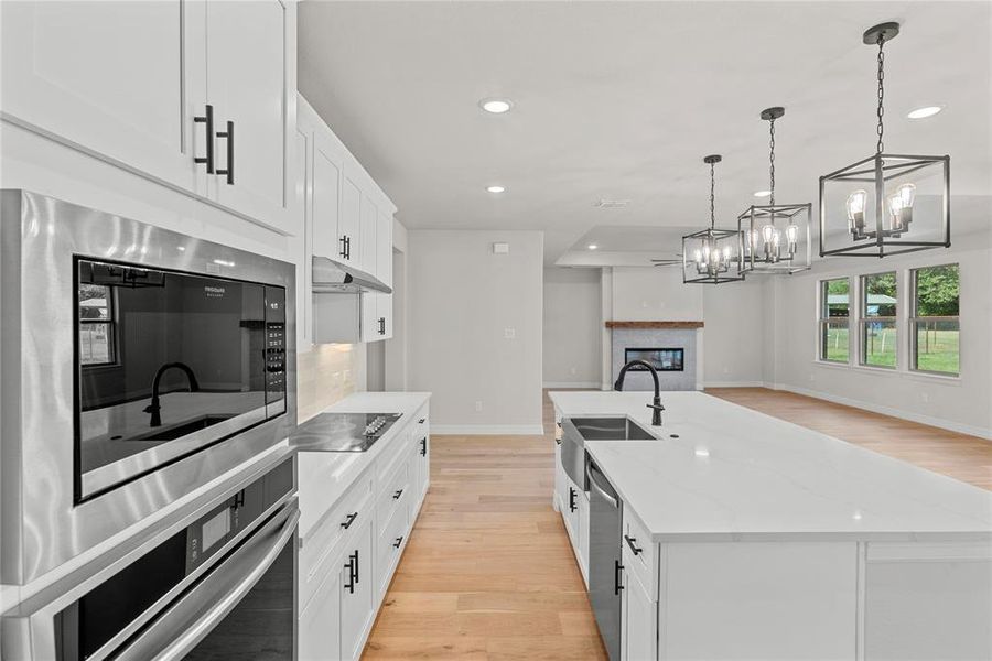 Kitchen featuring light wood flooring, tasteful backsplash, SS appliances, light countertops, and white cabinets