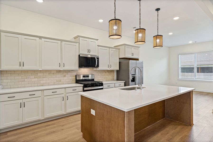 Open-concept kitchen featuring white shaker cabinetry, light-toned subway tile backsplash, and stainless steel appliances Open-concept kitchen featuring white shaker cabinetry, light-toned subway tile backsplash, and stainless steel appliances