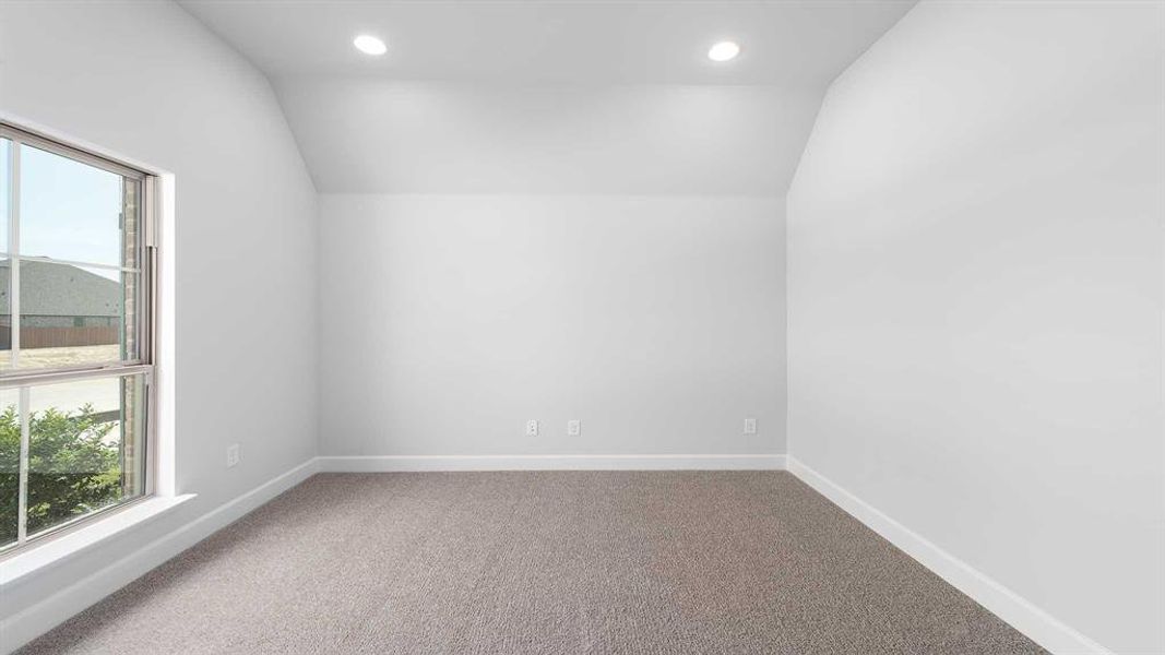 Carpeted empty room featuring vaulted ceiling