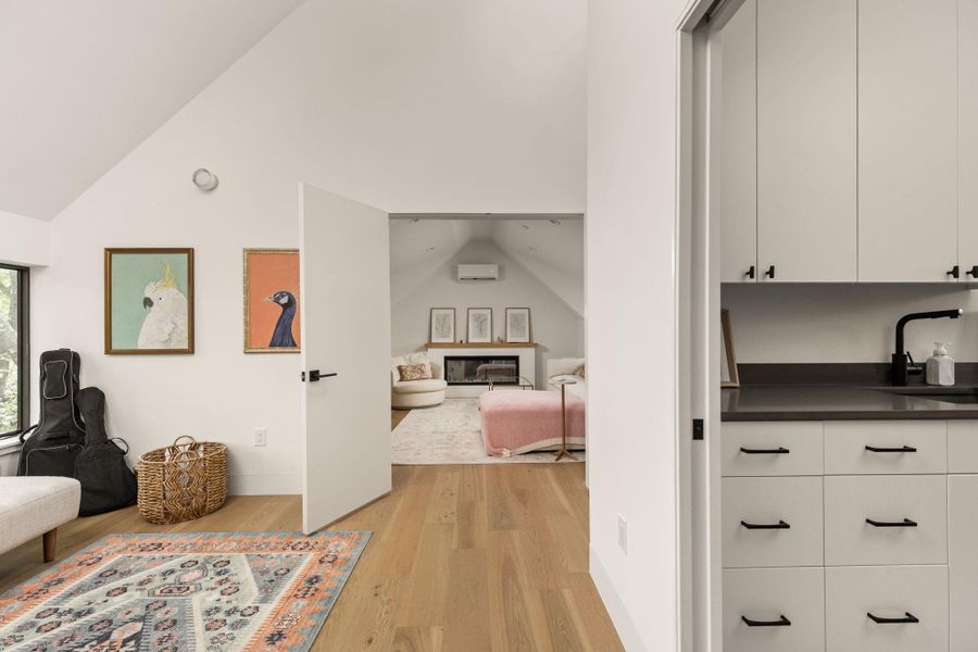Hardwood floors guide you to a living area featuring a fireplace and sloped ceilings. Hardwood floors guide you to a living area featuring a fireplace and sloped ceilings.