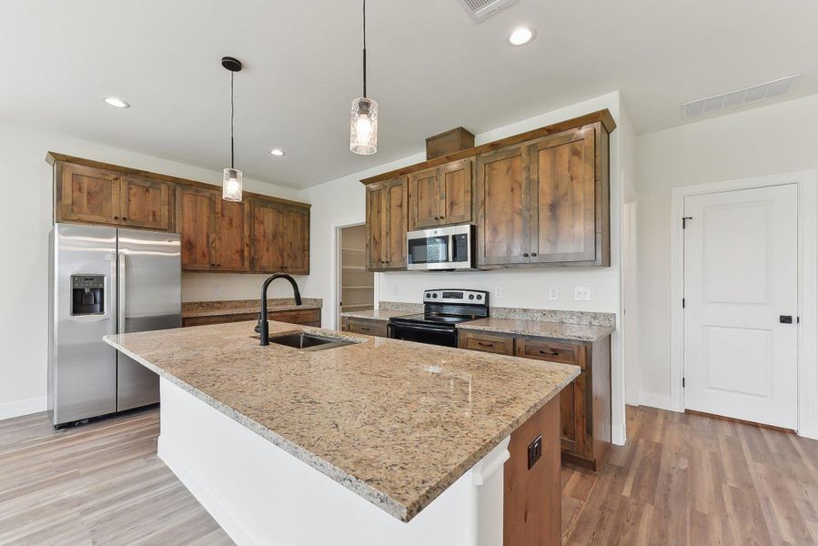 Kitchen featuring light wood-style flooring, visible vents, stainless steel appliances, and a sink