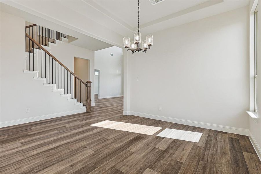 Empty room featuring a chandelier and dark wood-type flooring