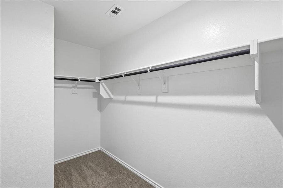 Primary walk in closet with carpet, rods and shelving Primary walk in closet with carpet, rods and shelving