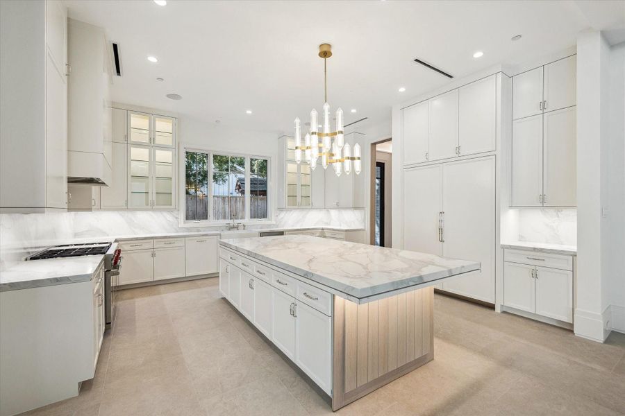 Show-stopping kitchen centered around a seating island, showcasing a sleek 60" paneled built-in Sub-Zero side by side refrigerator and full-height custom cabinetry.