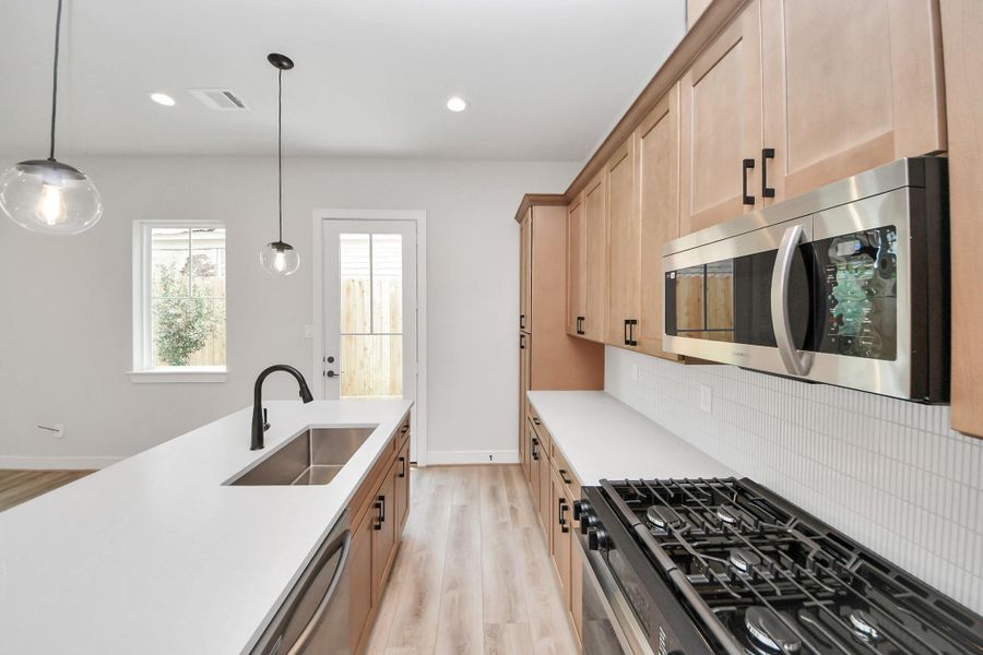 Sleek back splash, stainless steel appliances, and modern fixtures.