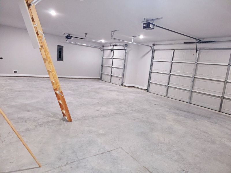 Spacious three-car garage with an access ladder to the spacious attic.