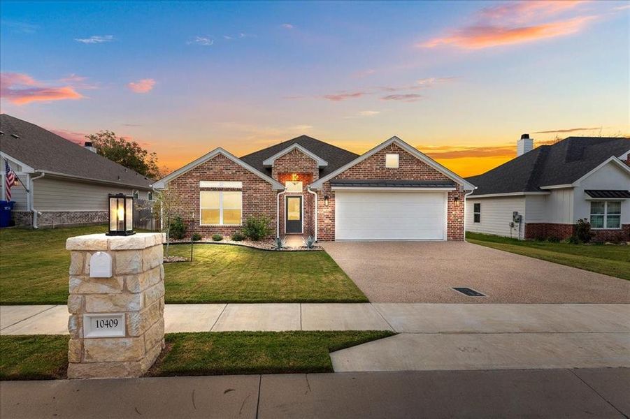 View of front of home featuring driveway, a front yard, and a garage