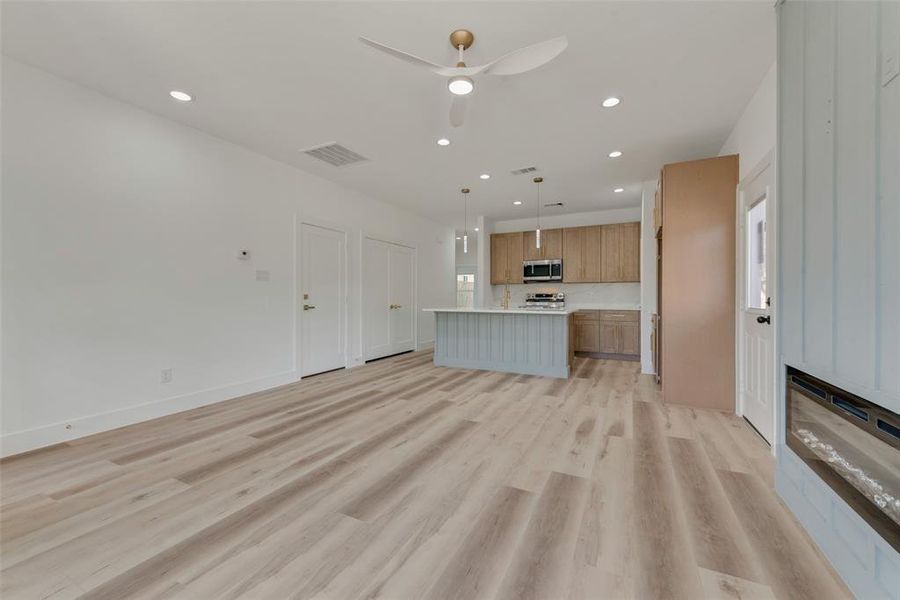 Unfurnished living room with ceiling fan and light hardwood / wood-style floors