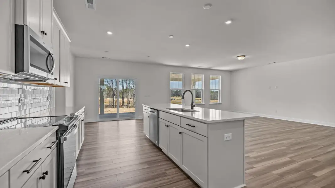 Open concept kitchen and family room with large windows and easy access to the covered porch; the Norris Design by DRB Homes Open concept kitchen and family room with large windows and easy access to the covered porch; the Norris Design by DRB Homes