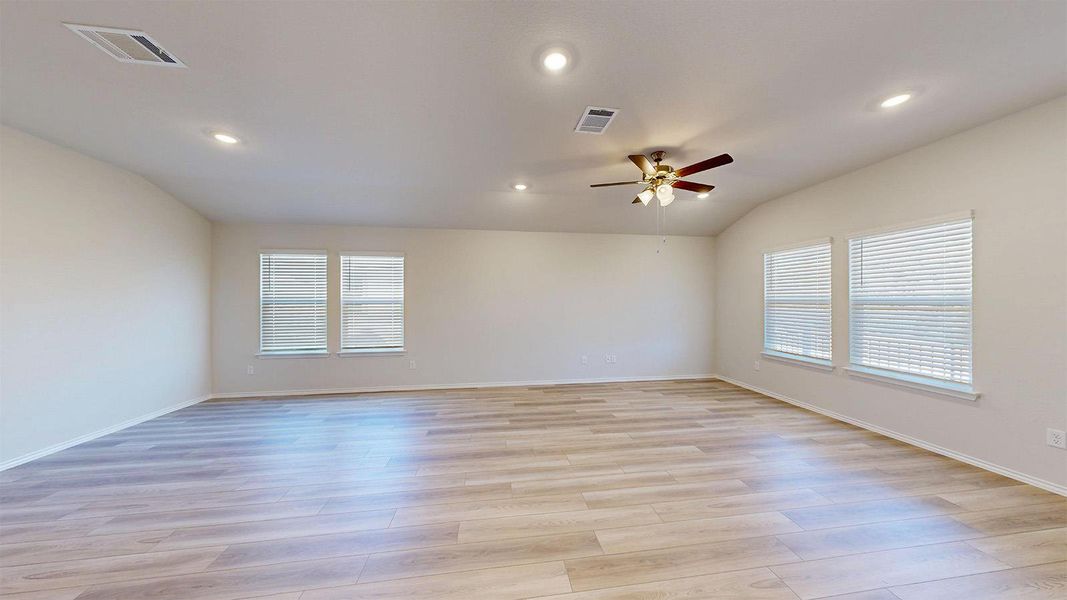 Spacious room featuring light wood-finish flooring, multiple windows with blinds, recessed lighting, and a ceiling fan