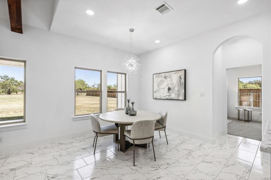 Tiled dining room featuring beam ceiling and a chandelier