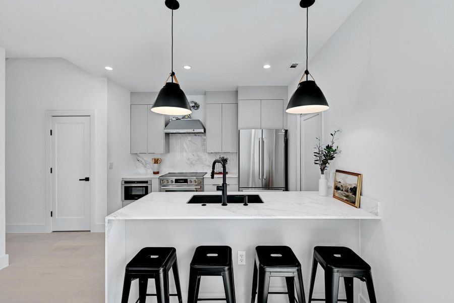 Kitchen with light quartz countertops, modern cabinets, and appliances with stainless steel finishes