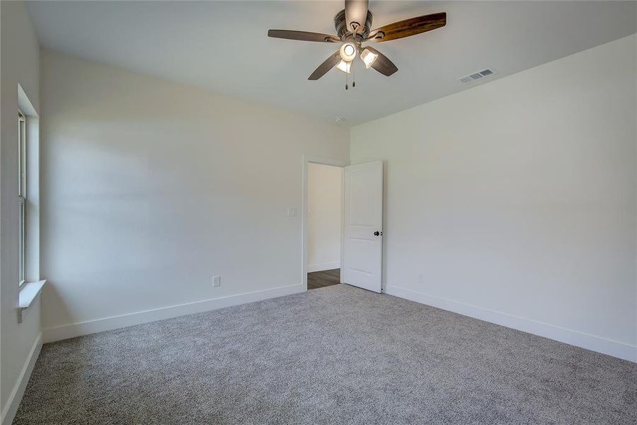Carpeted empty room featuring baseboards and ceiling fan Carpeted empty room featuring baseboards and ceiling fan