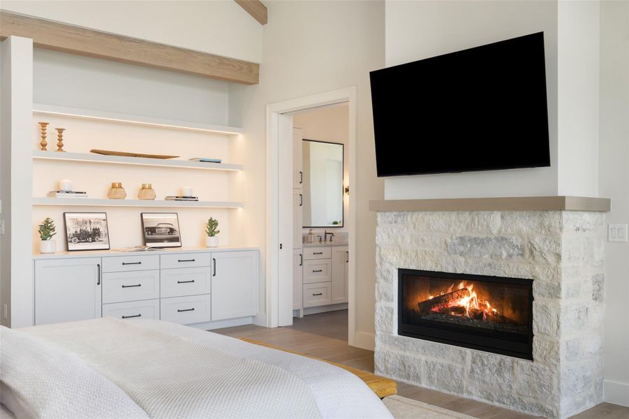 Bedroom with light wood-style floors, ensuite bathroom, and a fireplace