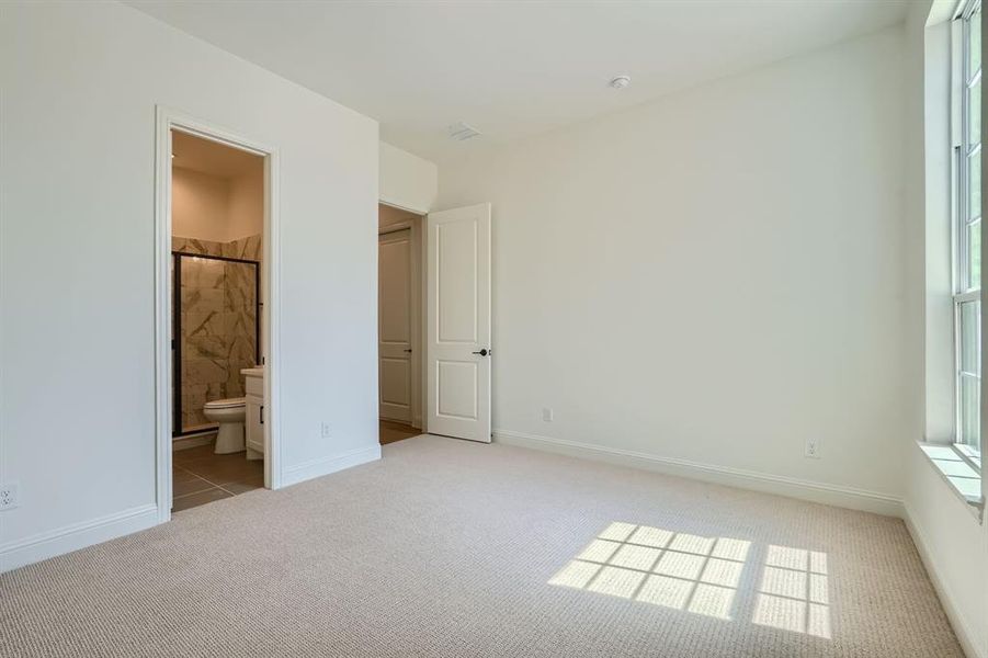 Unfurnished bedroom with ensuite bath and light colored carpet