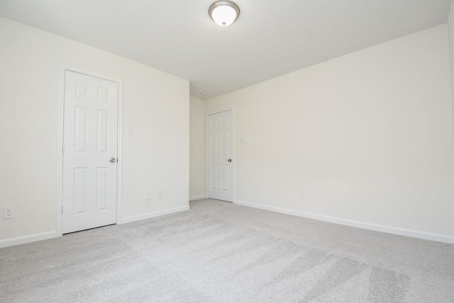 This is a spacious, well-lit room with neutral walls and carpeting, featuring a ceiling light fixture and two doors, offering a clean canvas for personalization. This is a spacious, well-lit room with neutral walls and carpeting, featuring a ceiling light fixture and two doors, offering a clean canvas for personalization.