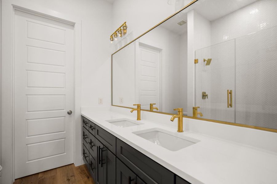 A well-lit bathroom features a spacious dual vanity with modern fixtures and a glass-enclosed shower. A well-lit bathroom features a spacious dual vanity with modern fixtures and a glass-enclosed shower.