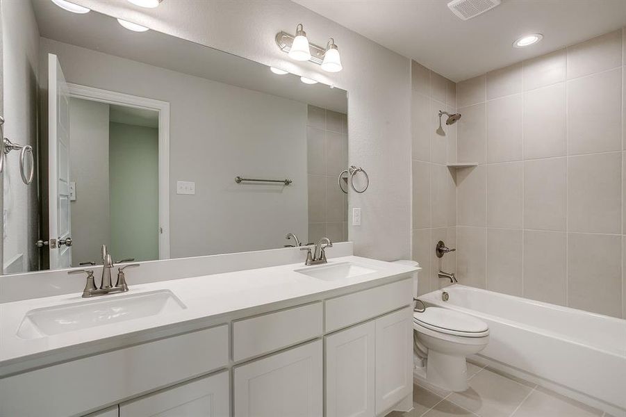 Bathroom with double vanity, shower / bathtub combination, light tile patterned floors, and recessed lighting