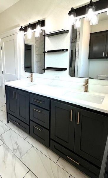 Full bathroom featuring double vanity and marble look tile flooring