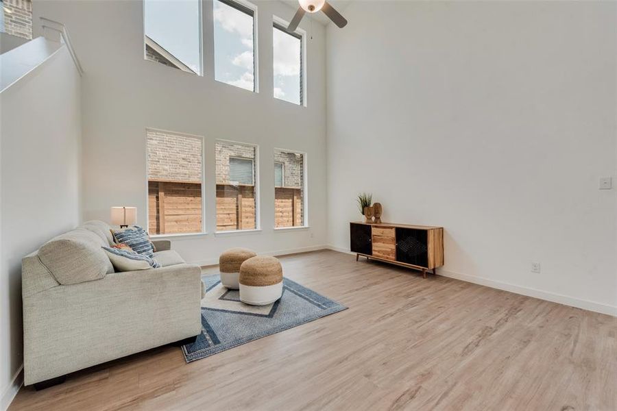 Living room with light hardwood / wood-style flooring, a high ceiling, and ceiling fan