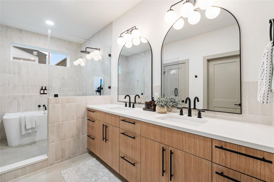 With a layout designed for ease and indulgence, this primary bathroom combines luxury and functionality—featuring a double vanity with quartz counters, matte black fixtures, and ample storage. A glass-enclosed shower and freestanding tub sit beneath a clerestory window, bathing the space in soft natural light for a spa-like experience every day.