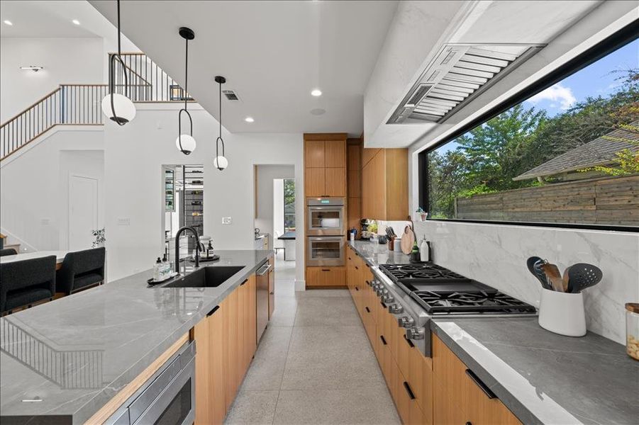 Kitchen with modern cabinets, recessed lighting, hanging light fixtures, stainless steel appliances, and dark stone counters