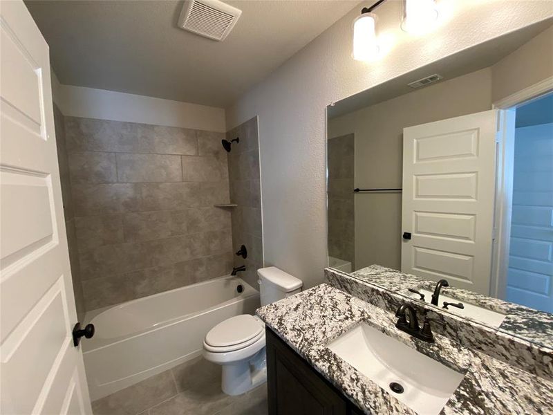 Full ensuite bathroom 3 with granite vanity, tub/shower combo, and 12x24 tile on floor & shower walls