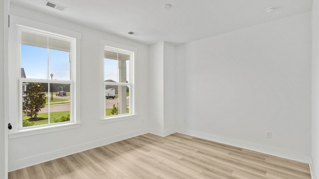 Comfortable secondary bedroom with large windows at Chestnut Farms by DRB Homes