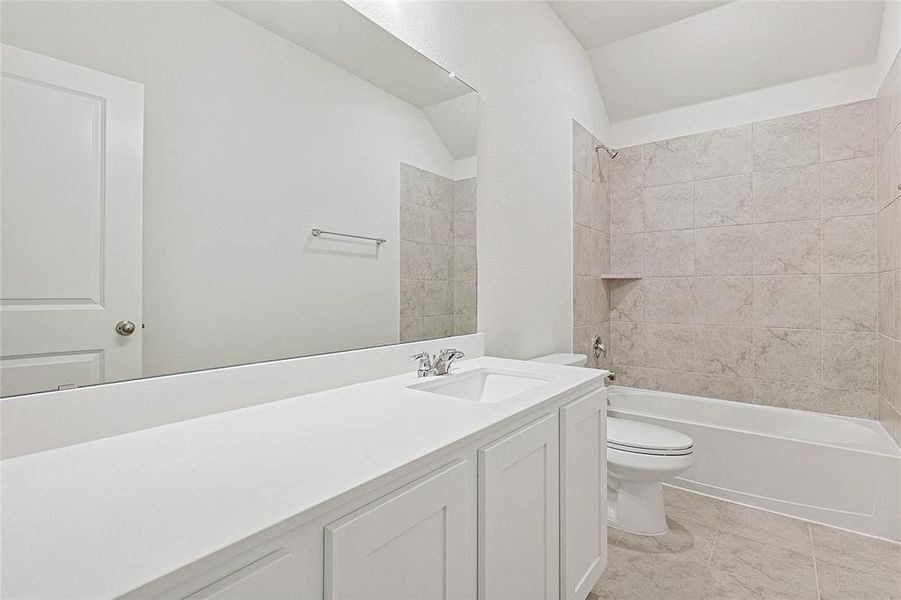 Bathroom featuring vanity,  shower combination, and vaulted ceiling