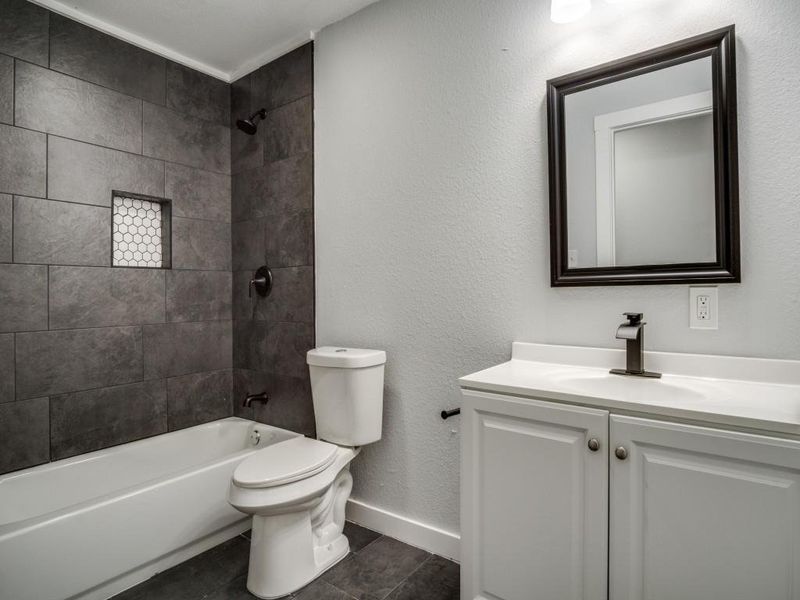Full bathroom featuring tile patterned floors, vanity, tiled shower / bath combo, and toilet Full bathroom featuring tile patterned floors, vanity, tiled shower / bath combo, and toilet