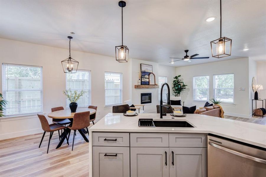 Kitchen with ceiling fan, sink, hanging light fixtures, light hardwood / wood-style flooring, and dishwasher