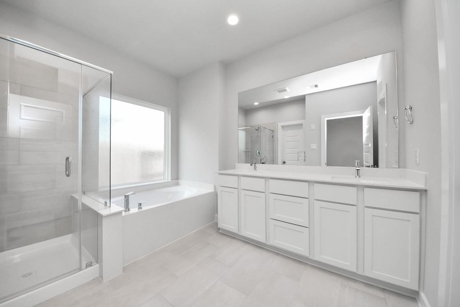 Escape to a spa-like oasis in this primary bathroom. Enjoy a walk-in shower with tile surround, a separate garden tub with custom detailing, and an elegant vanity featuring light countertops, modern hardware, and beautiful vanity lights. Experience luxury and relaxation in every detail.
