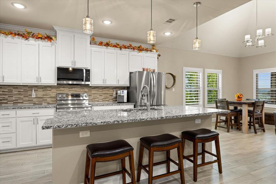 Kitchen with backsplash, light wood-style floors, white cabinets, stainless steel appliances, and recessed lighting Kitchen with backsplash, light wood-style floors, white cabinets, stainless steel appliances, and recessed lighting