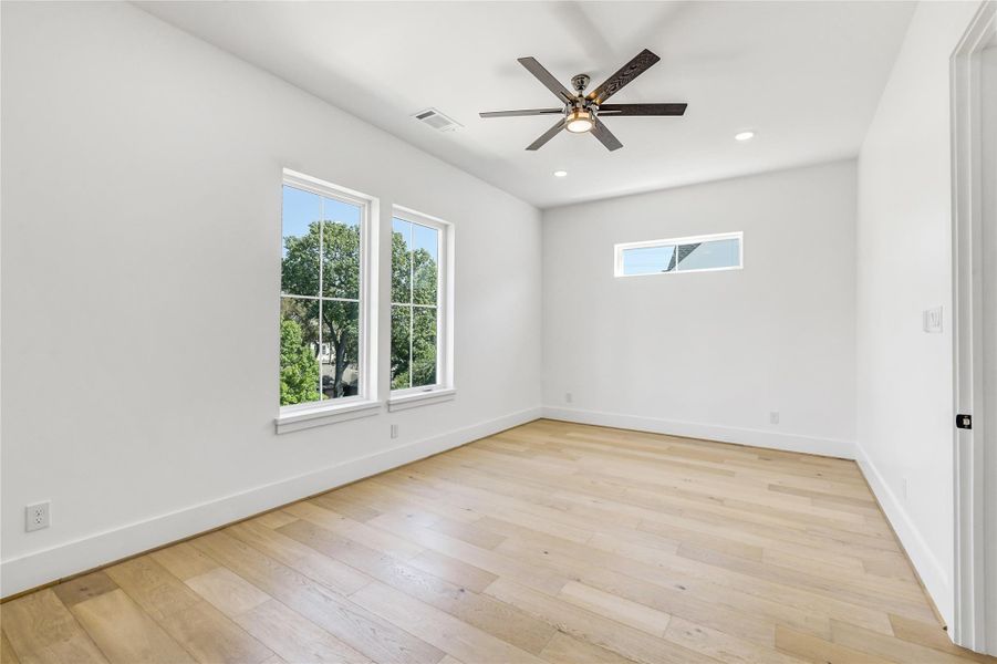 A bright and serene view of the room highlights its clean architectural lines and modern ceiling fan with integrated lighting. The clerestory window allows natural light while preserving privacy, and the neutral designer paint palette ensures a seamless flow with the rest of the home’s modern interior. A bright and serene view of the room highlights its clean architectural lines and modern ceiling fan with integrated lighting. The clerestory window allows natural light while preserving privacy, and the neutral designer paint palette ensures a seamless flow with the rest of the home’s modern interior.