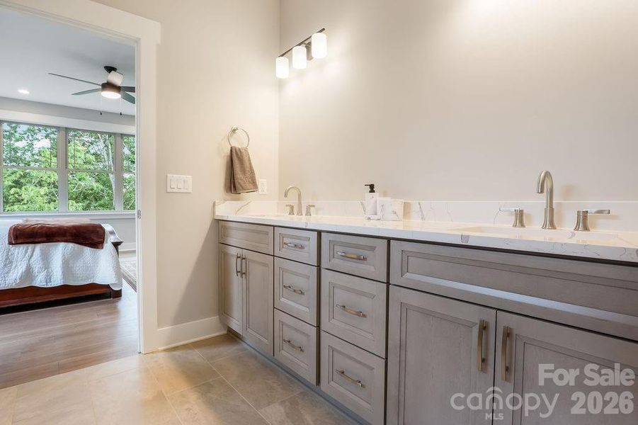 Primary bathroom with dual sinks and cabinetry.