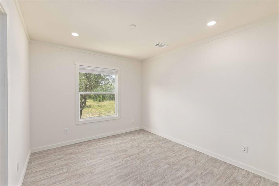 Room featuring wood-finish flooring, recessed lighting, crown molding, and a window with blinds