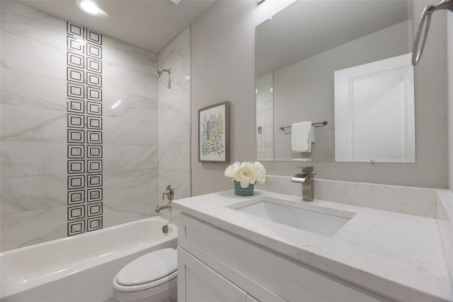 Full bathroom with vanity, tiled shower / bath combo, and toilet