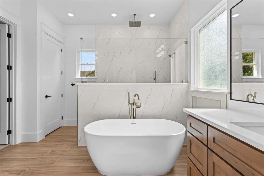 Bathroom featuring a freestanding bath, vanity, healthy amount of natural light, wood finish floors, and tile walls