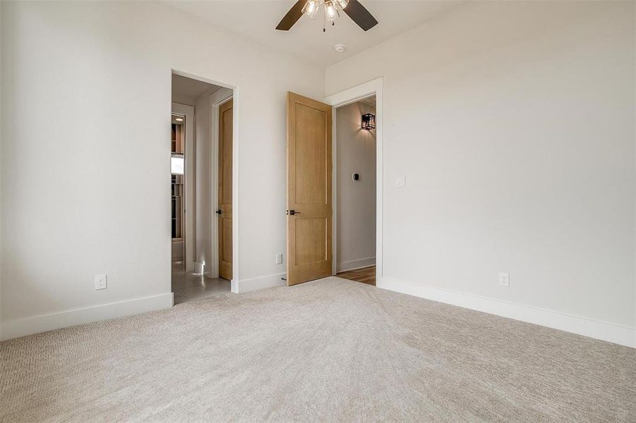 Unfurnished bedroom with light carpet and a ceiling fan
