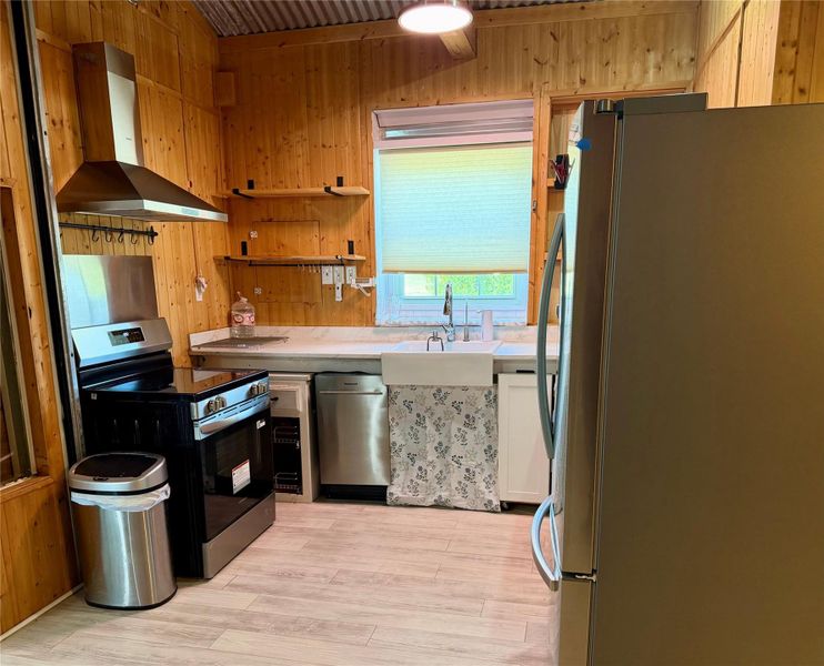 A well-appointed kitchen features rustic wood paneling, contemporary stainless steel appliances, and a farmhouse-style sink.