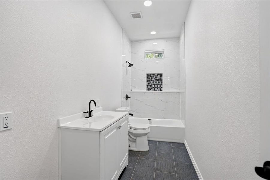 White vanity with a solid surface countertop and matte black faucet