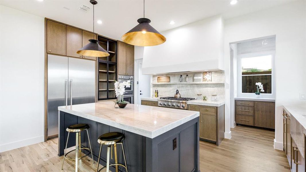 Kitchen with decorative backsplash, decorative light fixtures, light hardwood / wood-style flooring, and a kitchen island