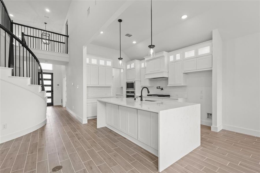 Kitchen with a center island with sink, white cabinets, and light hardwood / wood-style floors