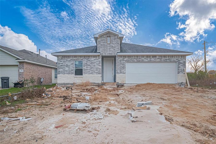 Even in its unfinished state, the brick and stone exterior hints at a striking presence. The covered recessed entryway adds a touch of depth to the façade, leading toward what promises to be a welcoming front entrance.