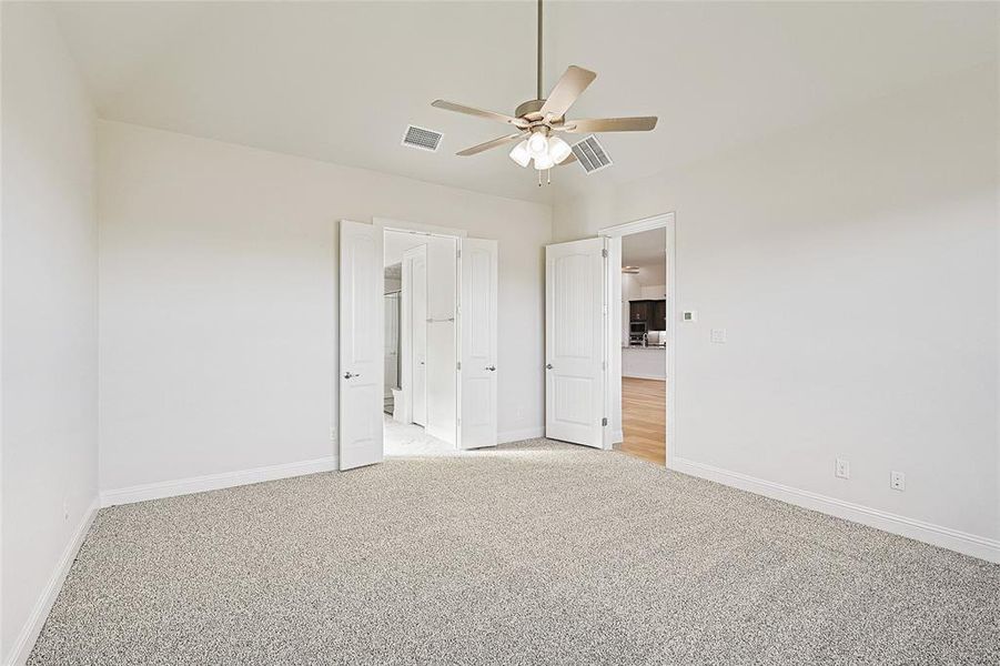 Unfurnished bedroom with ceiling fan and light colored carpet