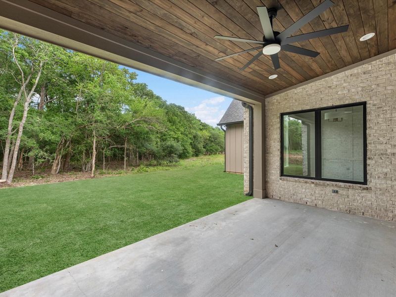 Private covered patio with wood-paneled ceiling and serene wooded views.