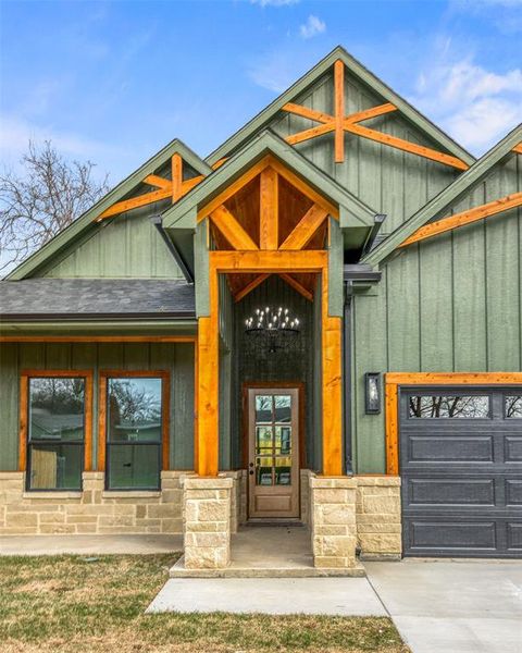 View of exterior entry featuring board and batten siding, a porch, an attached garage, and concrete driveway