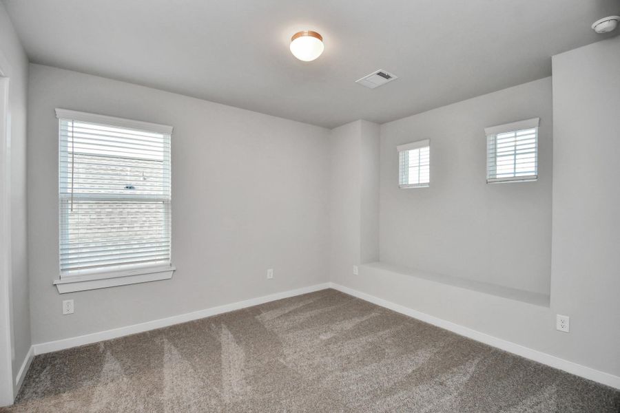 Secondary bedroom features plush carpeting, large windows that let in plenty of natural light, bright paint, and spacious closets. Sample photo of completed home with similar floor plan. Actual colors and selections may vary.