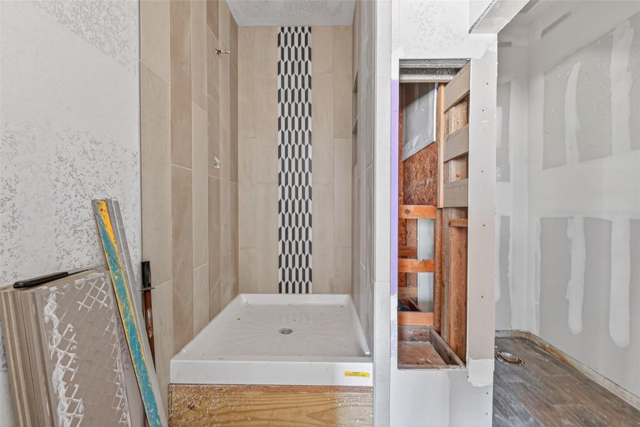 Main-level bath area under construction featuring shower installation in progress and unfinished surrounding space.