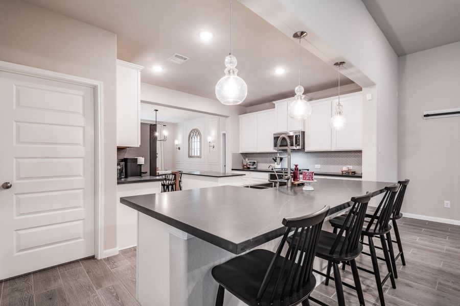 Modern kitchen with a spacious island featuring black countertops and bar seating. Pendant lights illuminate the area, complemented by white cabinetry and stainless steel appliances for a sleek, contemporary look. Modern kitchen with a spacious island featuring black countertops and bar seating. Pendant lights illuminate the area, complemented by white cabinetry and stainless steel appliances for a sleek, contemporary look.